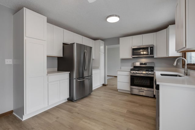 1097 Washington St, Bartlett, IL 60103 - kitchen featuring appliances with stainless steel finishes, a sink, light wood-type flooring, light countertops, and white cabinets