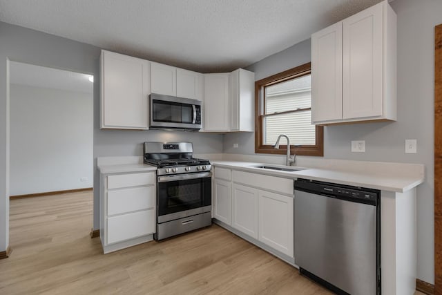 1097 Washington St, Bartlett, IL 60103 - kitchen featuring stainless steel appliances, a sink, light wood-style flooring, white cabinets, and a textured ceiling