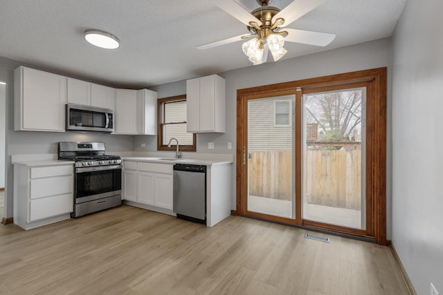 1097 Washington St, Bartlett, IL 60103 - kitchen with stainless steel appliances, a sink, light countertops, white cabinets, and light wood-style flooring