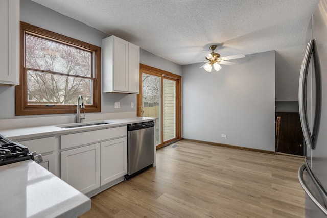 1097 Washington St, Bartlett, IL 60103 - kitchen with appliances with stainless steel finishes, a sink, white cabinetry, light countertops, and a textured ceiling