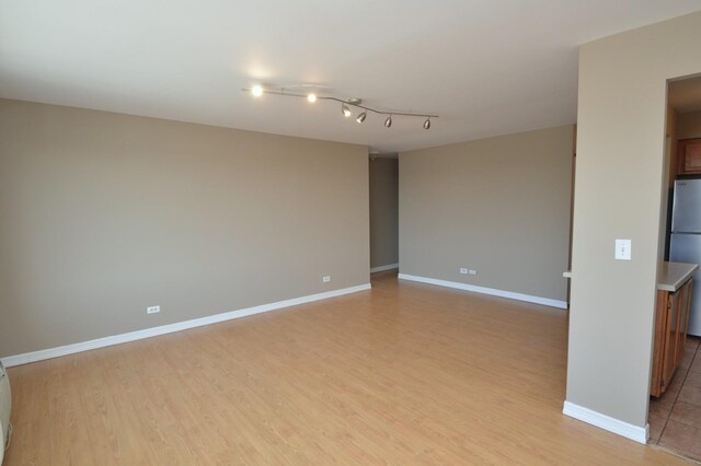 1227 S Harlem Ave Unit 511, Berwyn, IL 60402 - unfurnished room featuring baseboards, light wood finished floors, and rail lighting