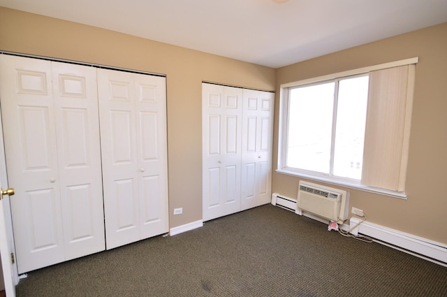 1227 S Harlem Ave Unit 511, Berwyn, IL 60402 - unfurnished bedroom with dark colored carpet, baseboard heating, baseboards, a wall mounted air conditioner, and multiple closets