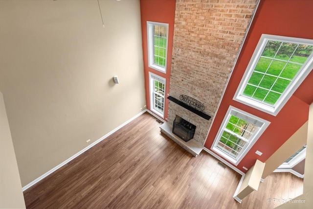 2097 Ivy Ridge Dr Unit 2097, Hoffman Estates, IL 60192 - unfurnished living room with a high ceiling, a fireplace, baseboards, wood finished floors, and plenty of natural light