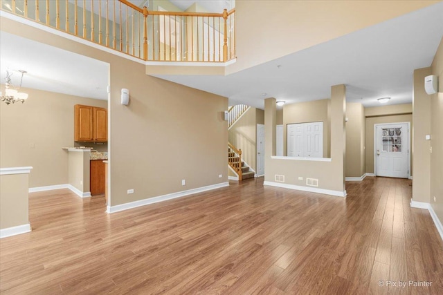 2097 Ivy Ridge Dr Unit 2097, Hoffman Estates, IL 60192 - unfurnished living room featuring stairway, visible vents, baseboards, light wood-type flooring, and a towering ceiling