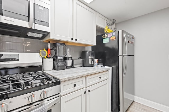9830 Sayre Ave Unit 6, Chicago Ridge, IL 60415 - kitchen featuring decorative backsplash, white cabinets, stainless steel appliances, baseboards, and light wood-type flooring
