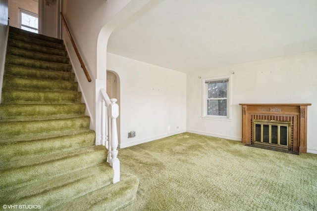 stairway featuring carpet floors, baseboards, and a fireplace