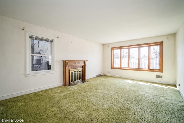 unfurnished living room featuring baseboards, a fireplace, carpet, and visible vents