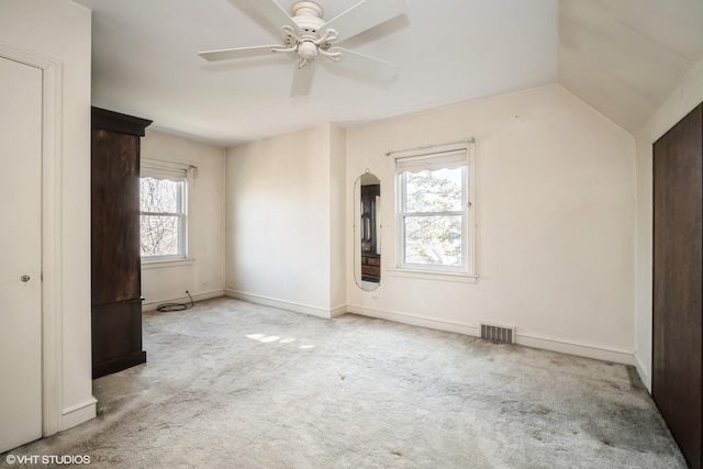 unfurnished bedroom featuring carpet flooring, baseboards, lofted ceiling, and visible vents