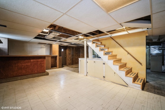 finished basement with a bar, stairs, and light floors