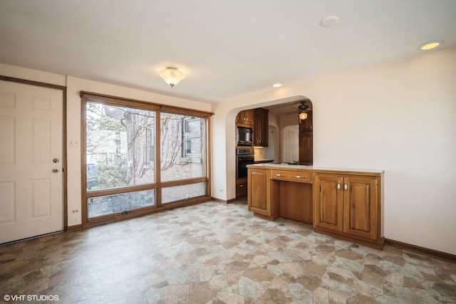 interior space featuring stone finish flooring, arched walkways, and baseboards
