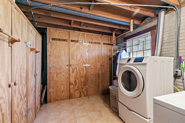 laundry area with washing machine and dryer, wooden walls, light tile patterned floors, and laundry area