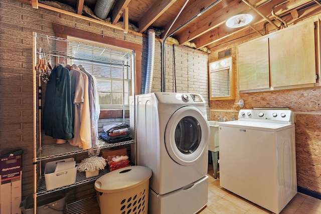 washroom featuring washing machine and clothes dryer, cabinet space, and light tile patterned floors