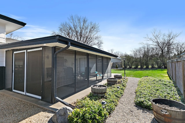 view of side of home featuring a sunroom, fence, and a yard