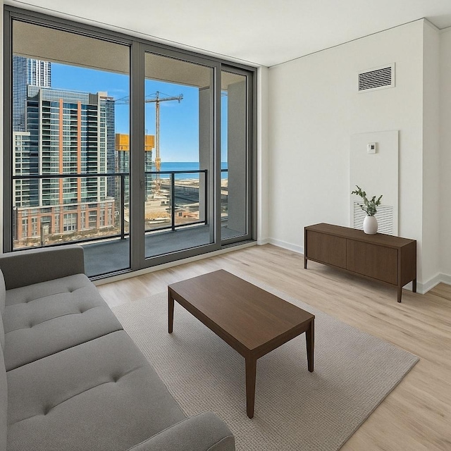 living area featuring expansive windows, wood finished floors, visible vents, and baseboards