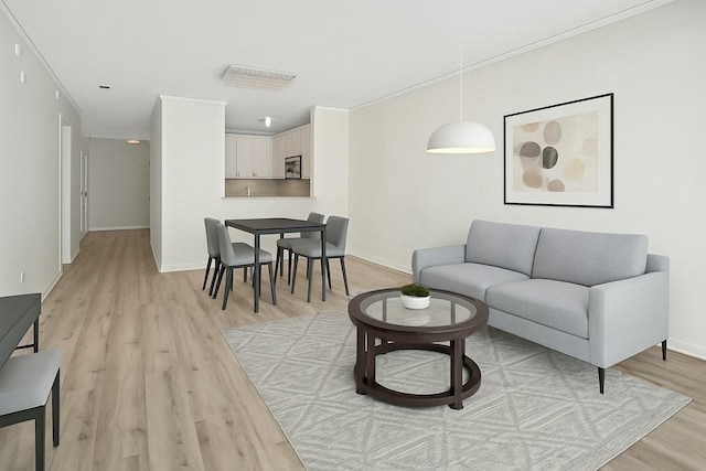 living room featuring baseboards, crown molding, and light wood finished floors