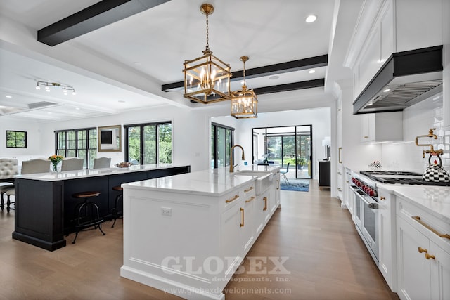 1544 Longvalley Rd, Glenview, IL 60025 - kitchen featuring a kitchen island with sink, light wood-style floors, beamed ceiling, range with two ovens, and a sink