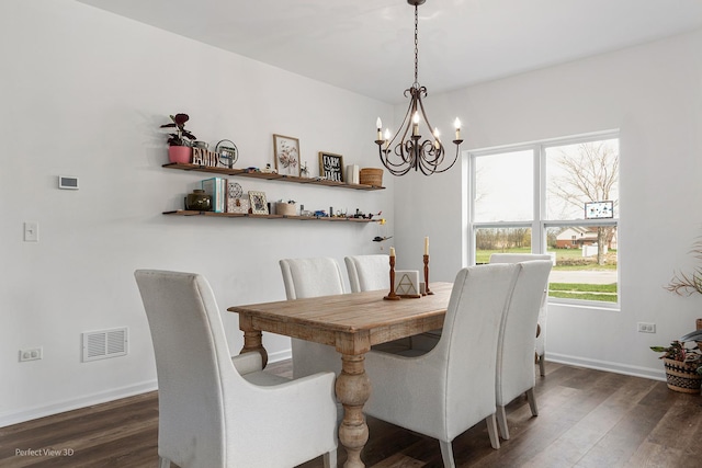 dining area featuring dark wood-type flooring, a chandelier, and baseboards