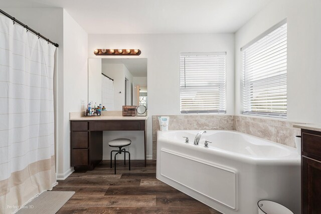 bathroom featuring wood finished floors, vanity, and a garden tub