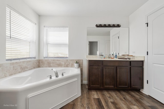 full bath featuring a garden tub, wood finished floors, and double vanity