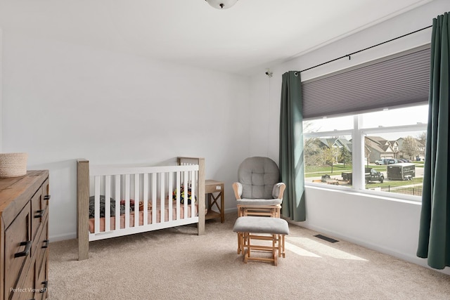 carpeted bedroom with a crib and baseboards