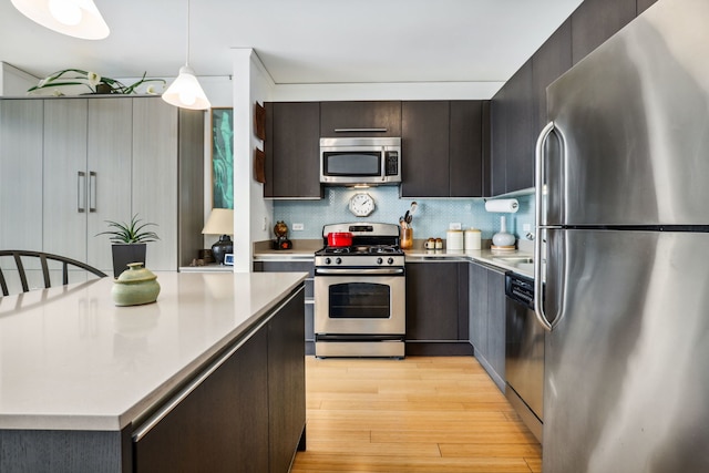 225 N Columbus Dr Unit 5305, Chicago, IL 60601 - kitchen featuring appliances with stainless steel finishes, light countertops, light wood-style flooring, dark brown cabinets, and decorative light fixtures