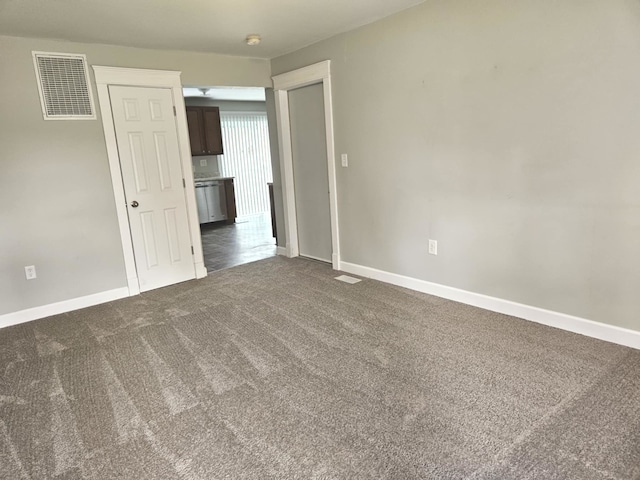 spare room with baseboards, dark colored carpet, and visible vents