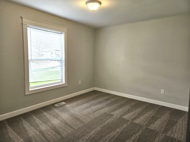 empty room with dark carpet, baseboards, and visible vents