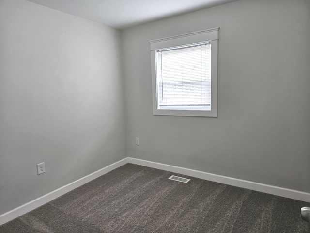 spare room with visible vents, baseboards, and dark carpet