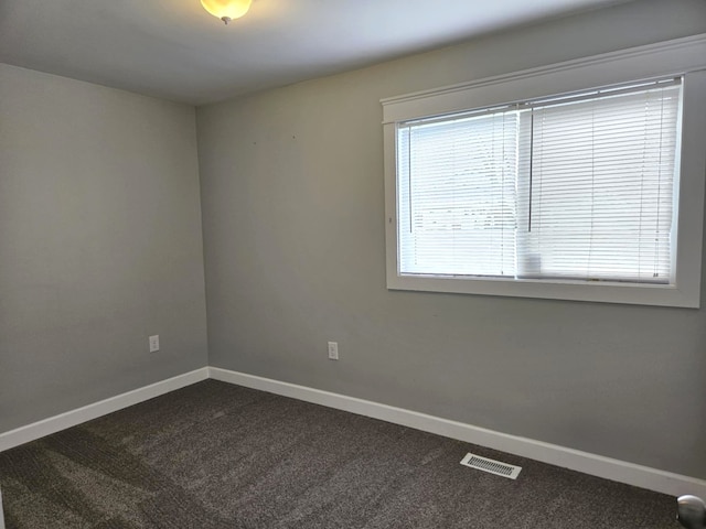 empty room with dark carpet, baseboards, and visible vents
