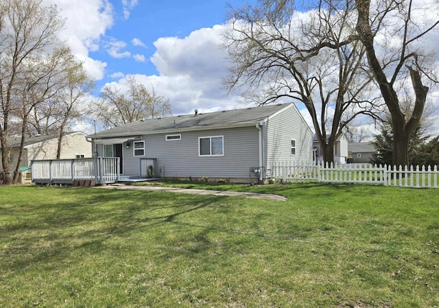 rear view of property with a yard, a deck, and fence