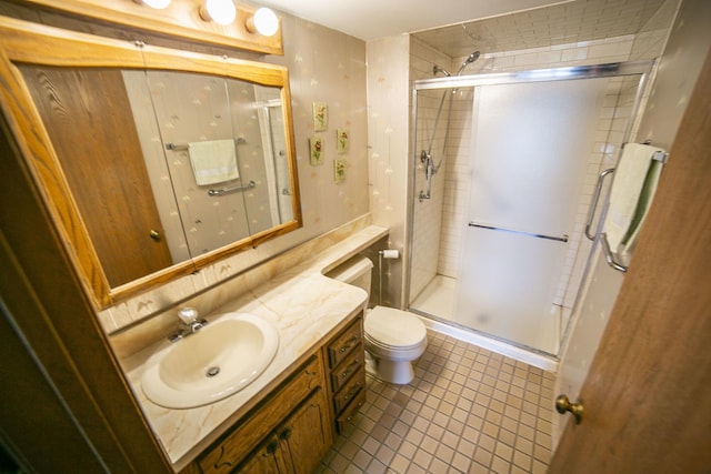 bathroom featuring toilet, vanity, a stall shower, and tile patterned flooring