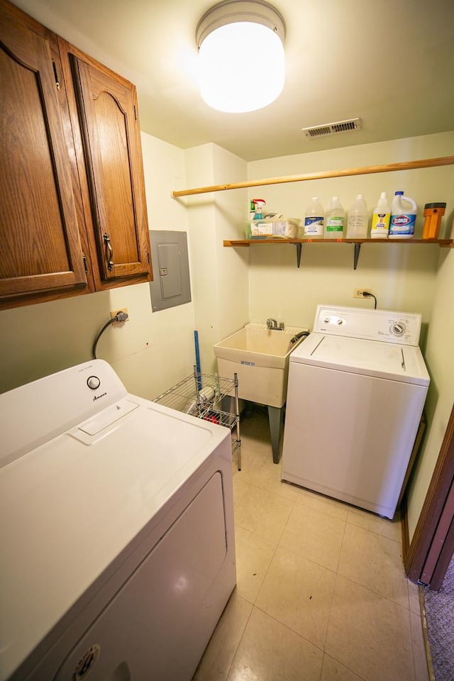 laundry area featuring independent washer and dryer, visible vents, electric panel, a sink, and cabinet space