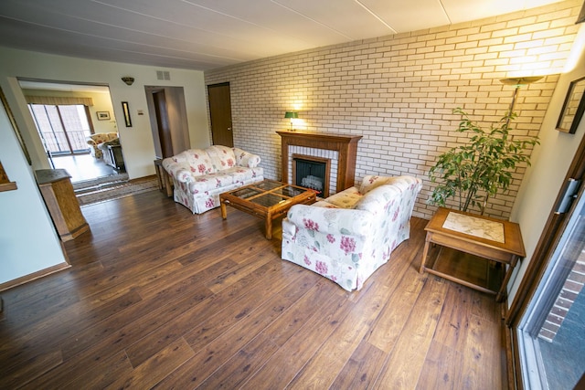 living room featuring brick wall, a fireplace, visible vents, and hardwood / wood-style floors