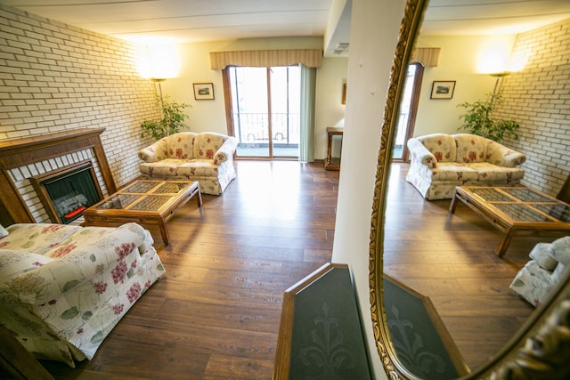 living room featuring brick wall, a fireplace, and hardwood / wood-style flooring