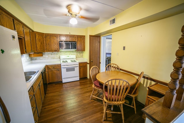 kitchen featuring visible vents, a sink, dark wood-style flooring, black appliances, and decorative backsplash