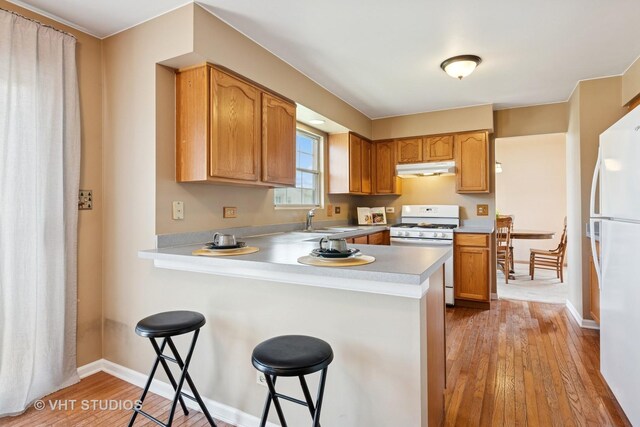 271 Valley Forge Ave, South Elgin, IL 60177 - kitchen with a sink, a kitchen bar, light wood-type flooring, white appliances, and a peninsula