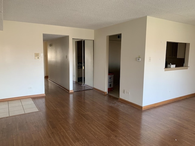 interior space featuring visible vents, a textured ceiling, baseboards, and wood finished floors