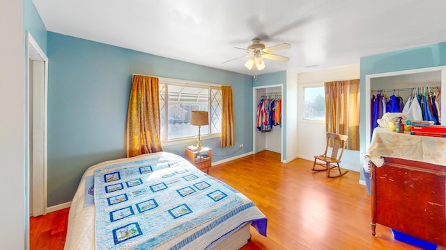 bedroom with two closets, wood finished floors, and baseboards