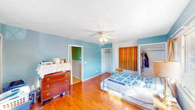 bedroom with baseboards, two closets, a ceiling fan, and wood finished floors