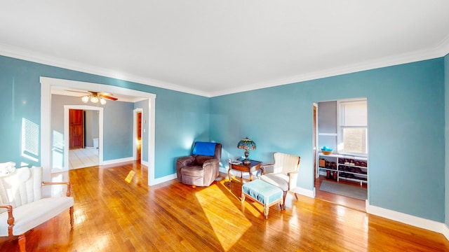 living area featuring crown molding, baseboards, and wood finished floors