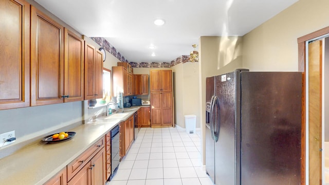 kitchen featuring brown cabinets, light countertops, black appliances, and a sink