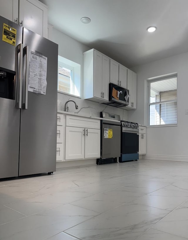 kitchen with light countertops, marble finish floor, plenty of natural light, and stainless steel appliances