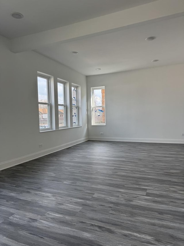 spare room featuring baseboards and dark wood finished floors