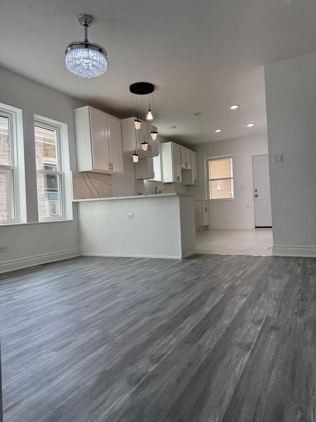 kitchen with white cabinets, dark wood-style flooring, open floor plan, a chandelier, and pendant lighting