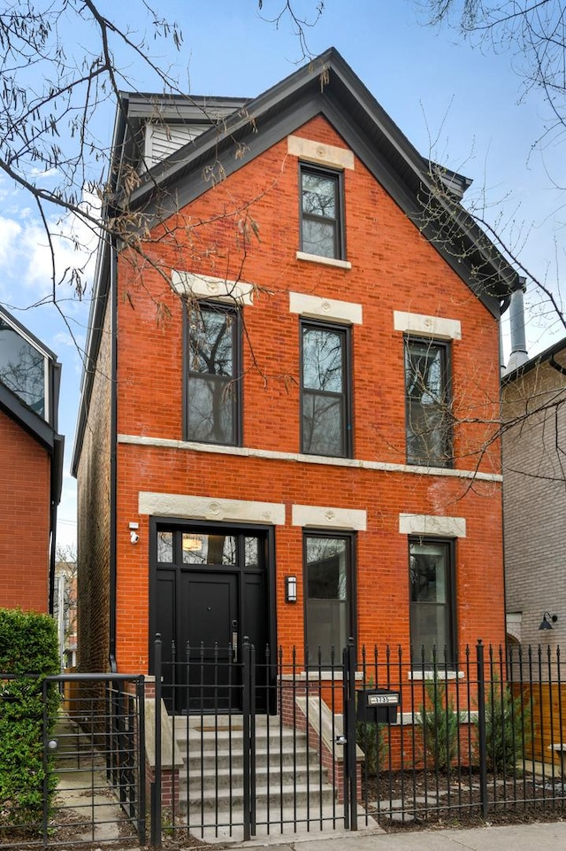 view of front facade featuring brick siding, a fenced front yard, and a gate