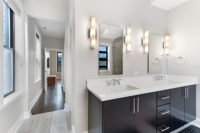 full bath featuring a sink, baseboards, and double vanity