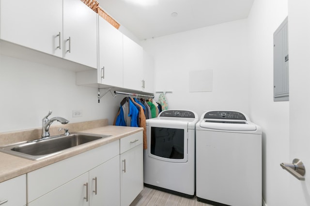 laundry area featuring light wood-style flooring, electric panel, a sink, cabinet space, and washer and clothes dryer