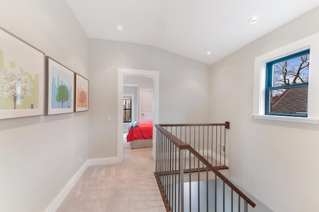 hallway featuring baseboards, carpet, an upstairs landing, and plenty of natural light