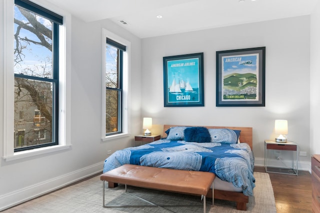 bedroom featuring visible vents, baseboards, and wood finished floors