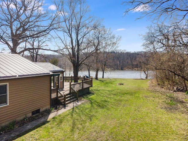 view of yard with a wooded view and a deck with water view